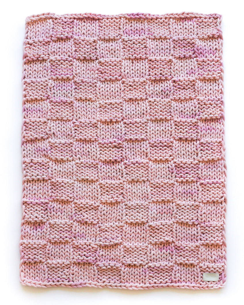 Marled pink pure cashmere chunky knit blanket in a checkered square knit pattern. 